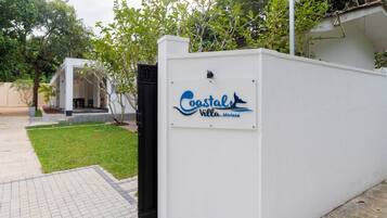 Un mur blanc avec une enseigne indiquant « Castal Villa-Mirissa » et un portail noir.