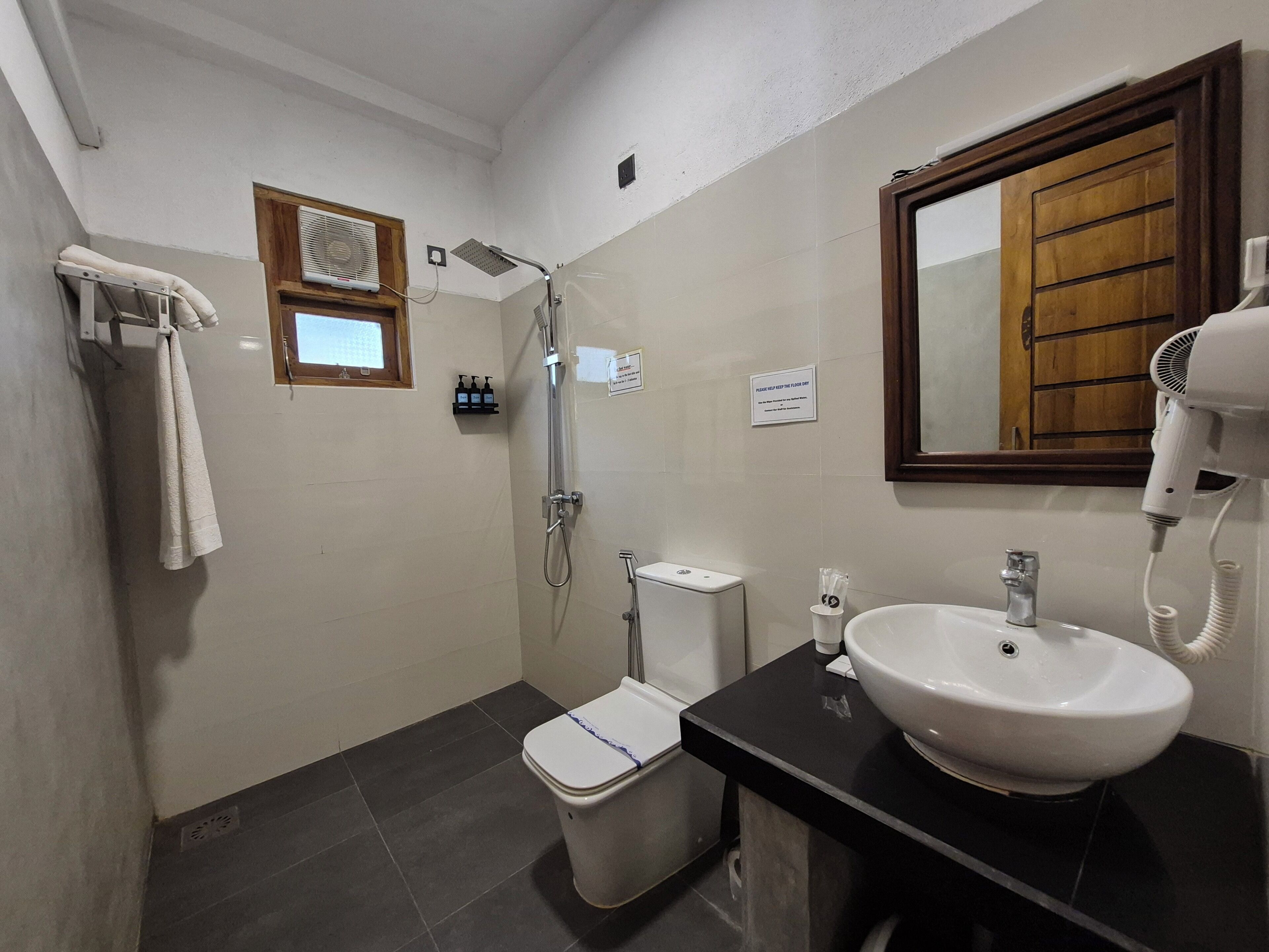 A bathroom with a shower, toilet, sink, and a hairdryer.