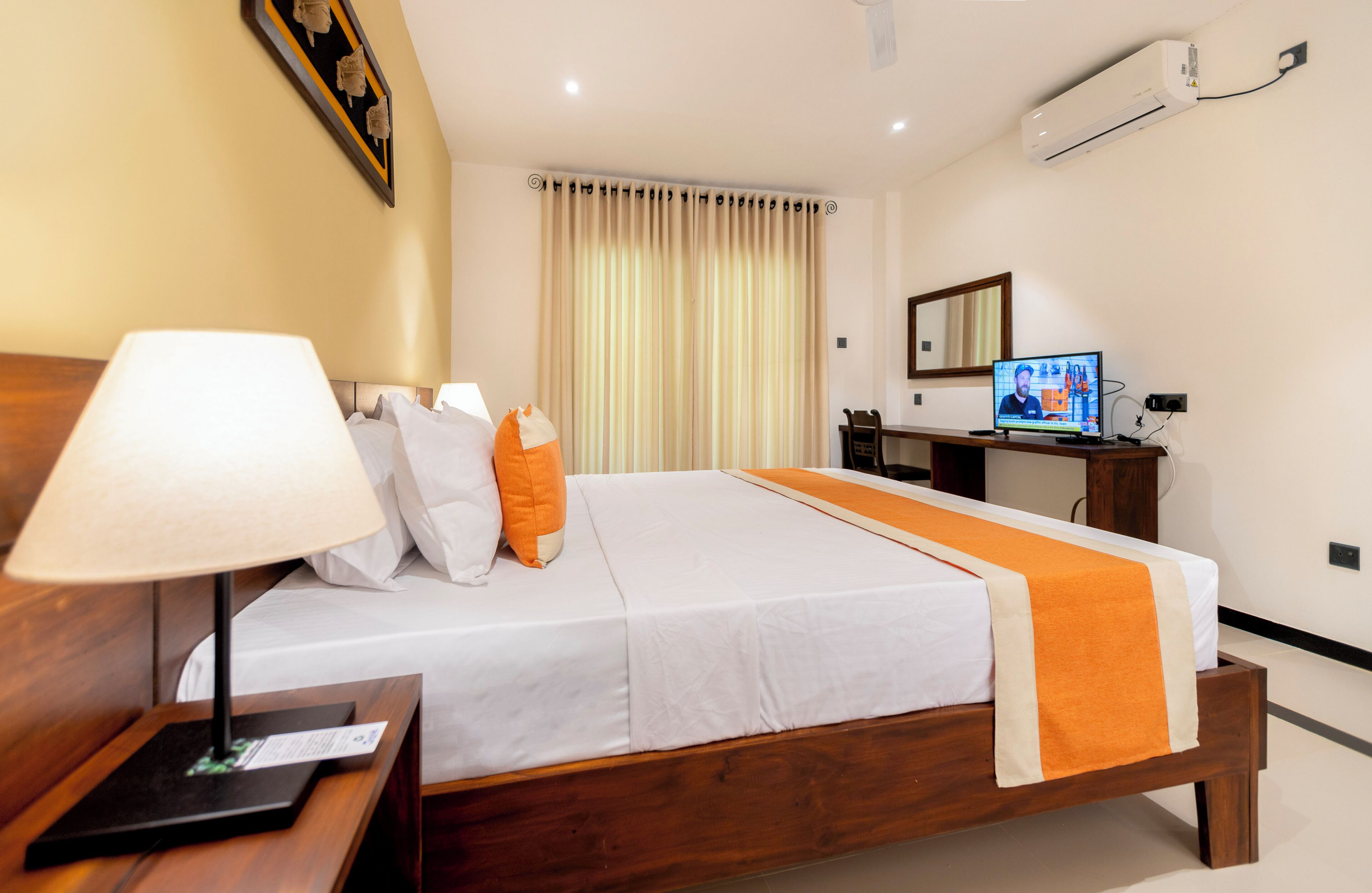 Une chambre d’hôtel équipée d’un lit, d’un bureau, d’une lampe, d’une télévision et d’un appareil de climatisation.