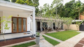 Una propiedad residencial con patio cubierto, césped y jardín con una planta en maceta.
