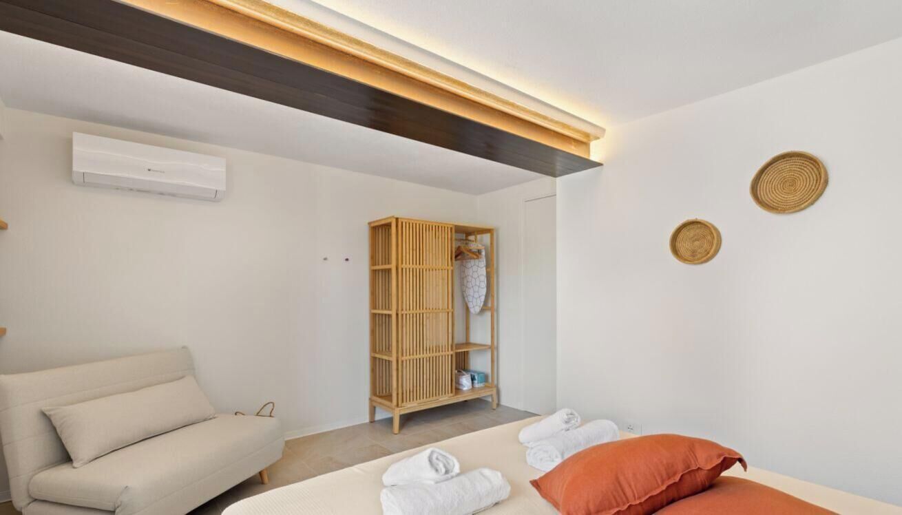 Ein modernes Hotelzimmer mit einem Bett, einer Couch, einem Holzschrank und einer Wand-Klimaanlage.