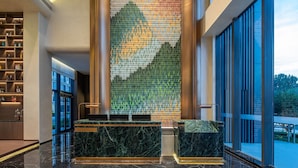 Un vestíbulo con mostrador de recepción, un papel tapiz decorativo y vistas al exterior.
