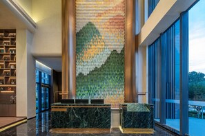 Un vestíbulo con mostrador de recepción, un papel tapiz decorativo y vistas al exterior.