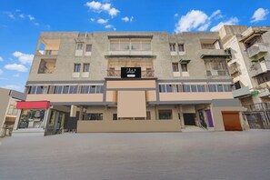 A multi-story building with a flat facade, large windows, and a sign indicating a company service. - Collection O Maninagar East (Ahmedabad)