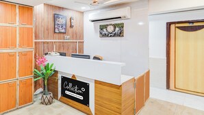 Un espace d’accueil avec un mur recouvert de panneaux en bois, un comptoir d’accueil et une horloge murale.