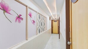 Un couloir doté d’un sol carrelé, d’une porte en bois et de motifs floraux décorant les murs.