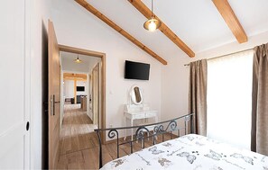 A bedroom with a bed, a dresser, a mirror, a TV, and a view of a balcony. - Stunning home in Jurdani (Jurdani)