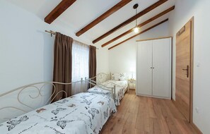 A bedroom with two single beds, a wardrobe, and a window with curtains. - Stunning home in Jurdani (Jurdani)