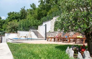 A pool area with a stone wall, a staircase, and lounge chairs. - Stunning home in Jurdani (Jurdani)