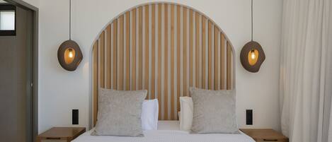 Un dormitorio moderno con una cama grande, cabecera de madera, dos mesitas de noche y dos lámparas de pared.