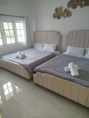 A hotel room with two beds, each with a headboard, pillows, and rolled towels.