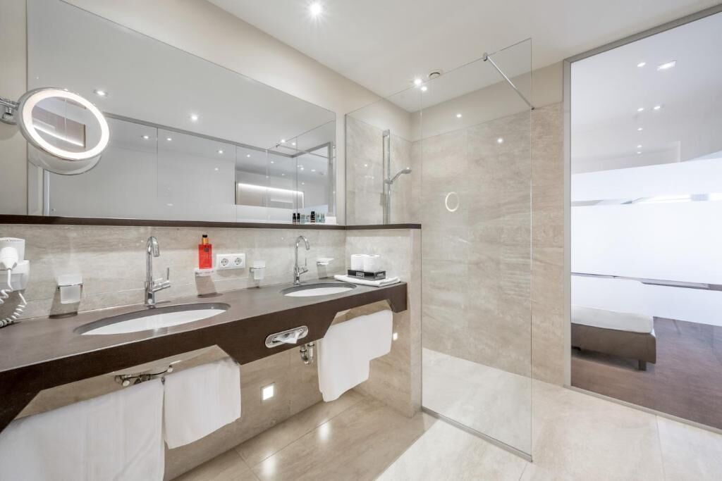 Een moderne badkamer met twee wasbakken, een grote spiegel en een douchecabine van glas.