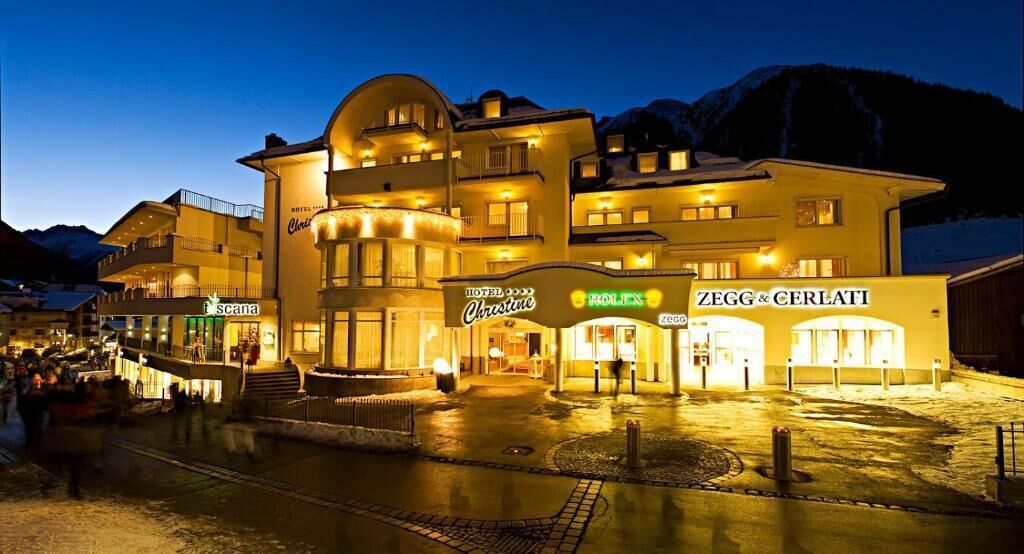 A hotel with multiple floors and balconies, a visible entrance, and adjacent shops.