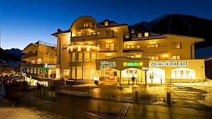 A hotel with multiple floors and balconies, a visible entrance, and adjacent shops. - Hotel Garni Christine - Ischgl (Ischgl)