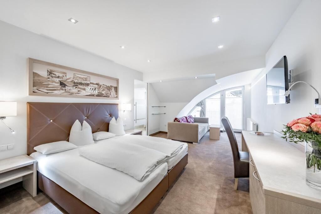 A modern hotel room with a large bed, a desk, and a TV.