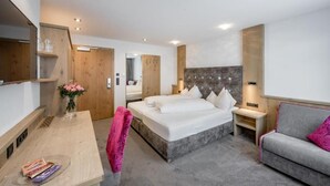 A modern hotel room with a large bed, bedside tables, a desk, and a sofa. - Hotel Garni Christine - Ischgl (Ischgl)