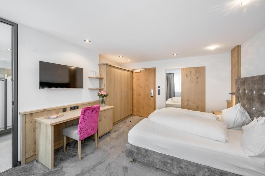 A modern bedroom with a bed, a desk, and a chair.