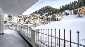 A snow-covered balcony with a view of a mountain and residential buildings.