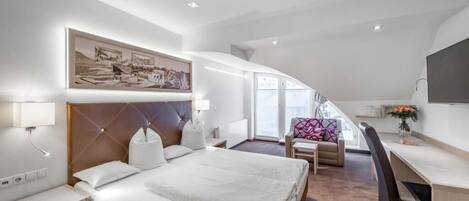 A modern hotel room with a bed, desk, chair, and artwork on the wall.