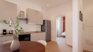 Una cocina moderna con armarios blancos, una campana extractora de acero inoxidable y un refrigerador.