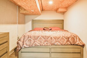 Ein Schlafzimmer mit Holzboden, einem Bett mit gemustertem Überwurf und einem Nachttisch.