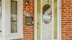 A brick building with a numbered door, a mailbox, and a window with blinds. - Essex Smart Stay (Essex)