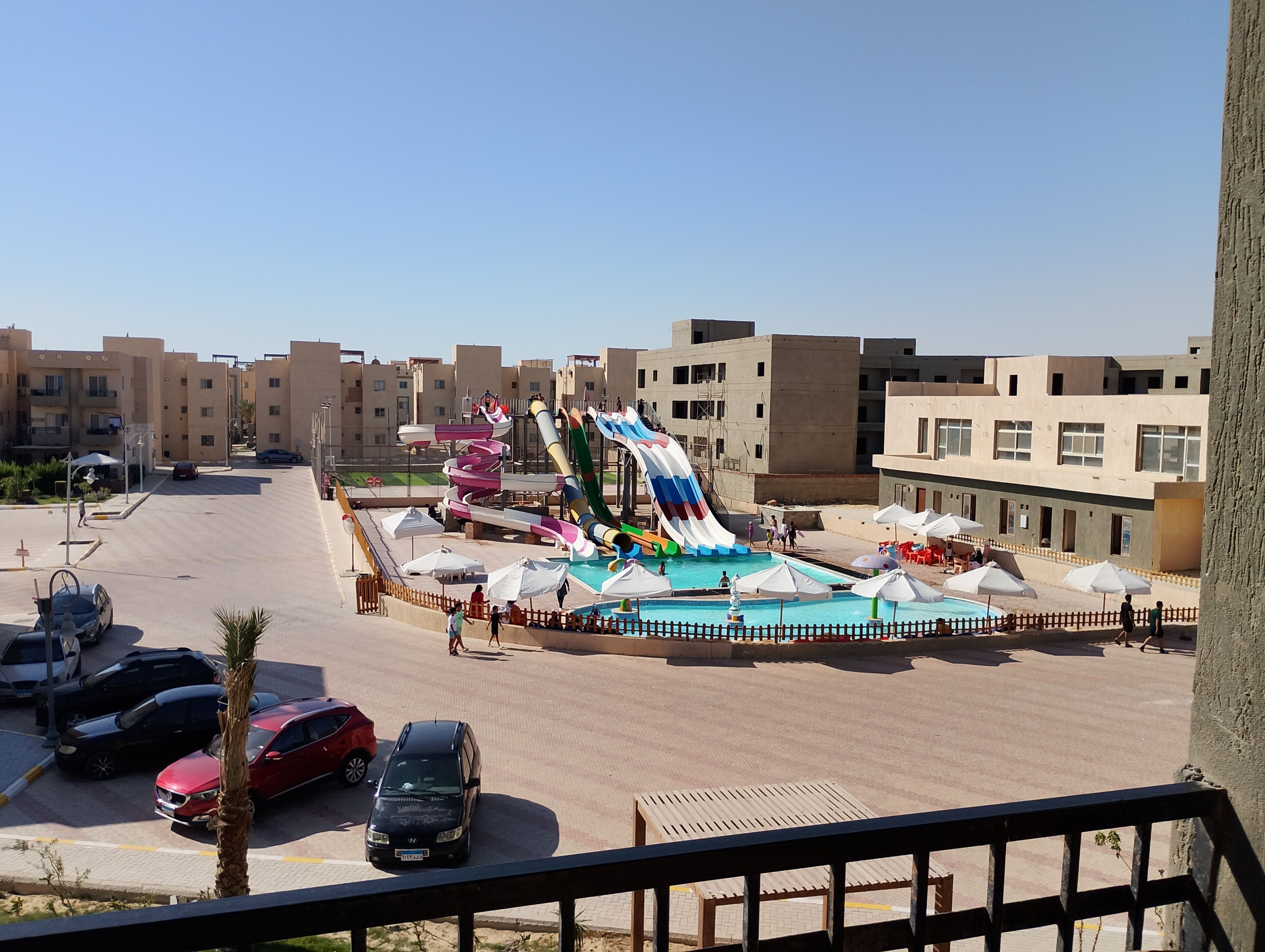 Um parque aquático com várias escorregas e uma piscina, tudo cercado por edifícios.