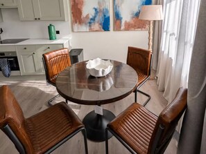 A dining area with a round table and four leather chairs, a green water dispenser, and abstract art on the wall. - Contemporary 1 Bedroom Apartment in Central London (London)