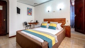 Habitación de hotel con cama, escritorio, silla, teléfono y televisor montado en la pared.