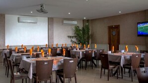 Un salón de conferencias con varias mesas, sillas y una pantalla de televisión en la pared.