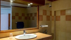 Un baño con lavamanos, espejo y ducha.