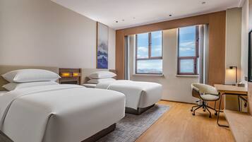Quarto de hotel moderno com duas camas, uma escrivaninha e uma cadeira.
