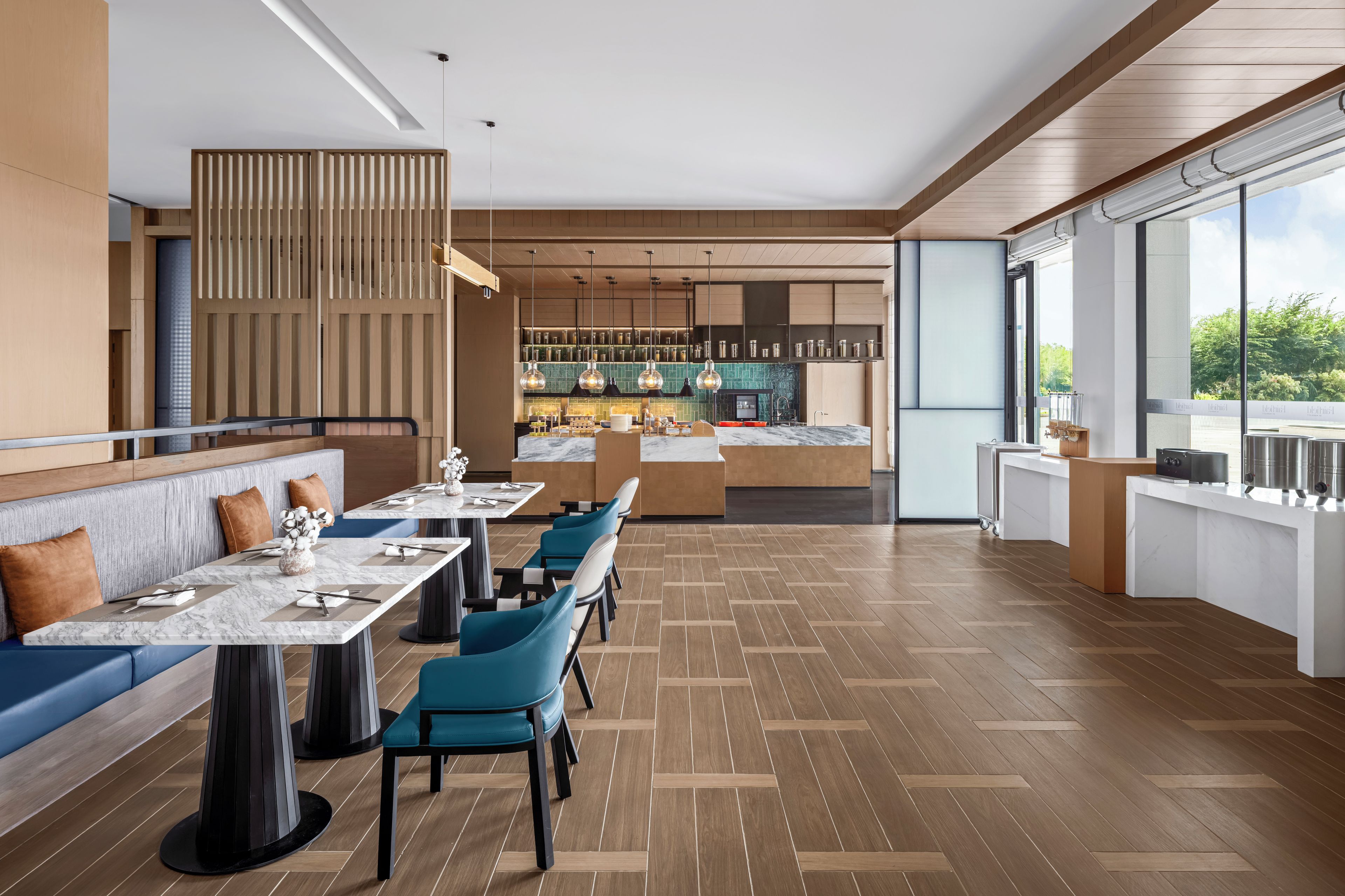 Un interior de restaurante moderno con suelo de madera, mesas de mármol y sillas azules.