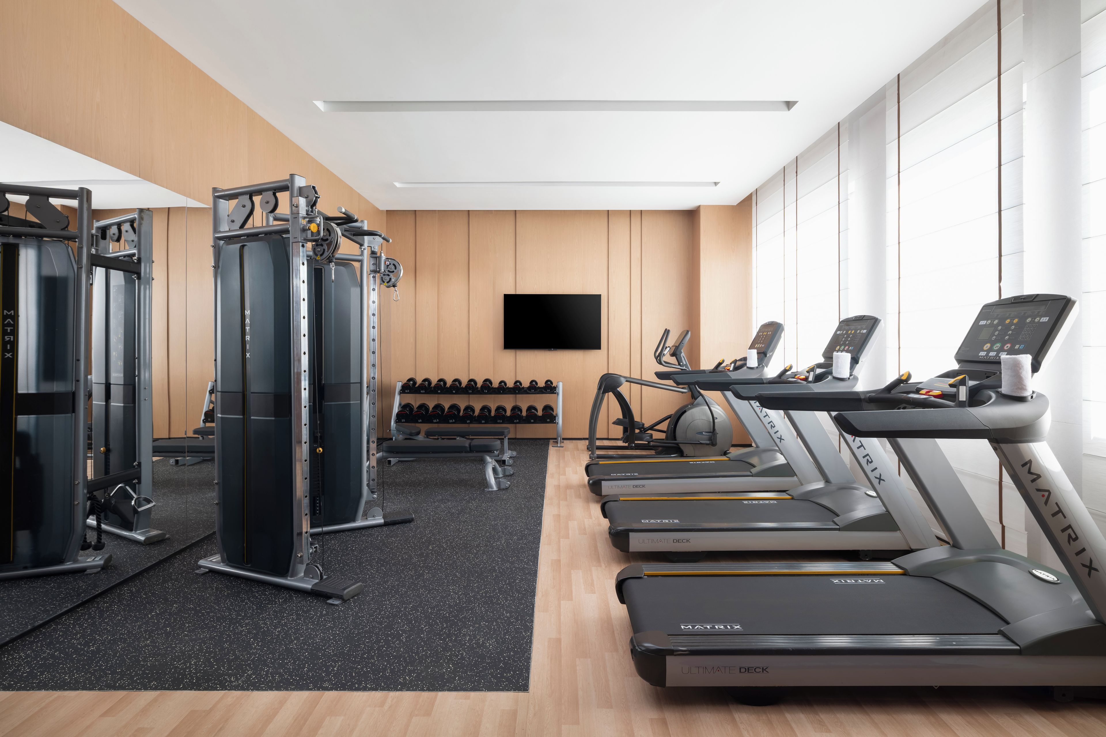 A gym with treadmills, a weight machine, and a wall-mounted TV.
