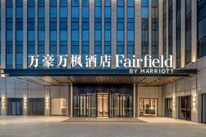 A hotel entrance with a modern facade, large glass windows, and a marquee sign above the doors.