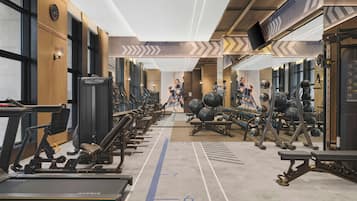 Un gimnasio con cintas de correr, bicicletas estáticas y máquinas de pesas.
