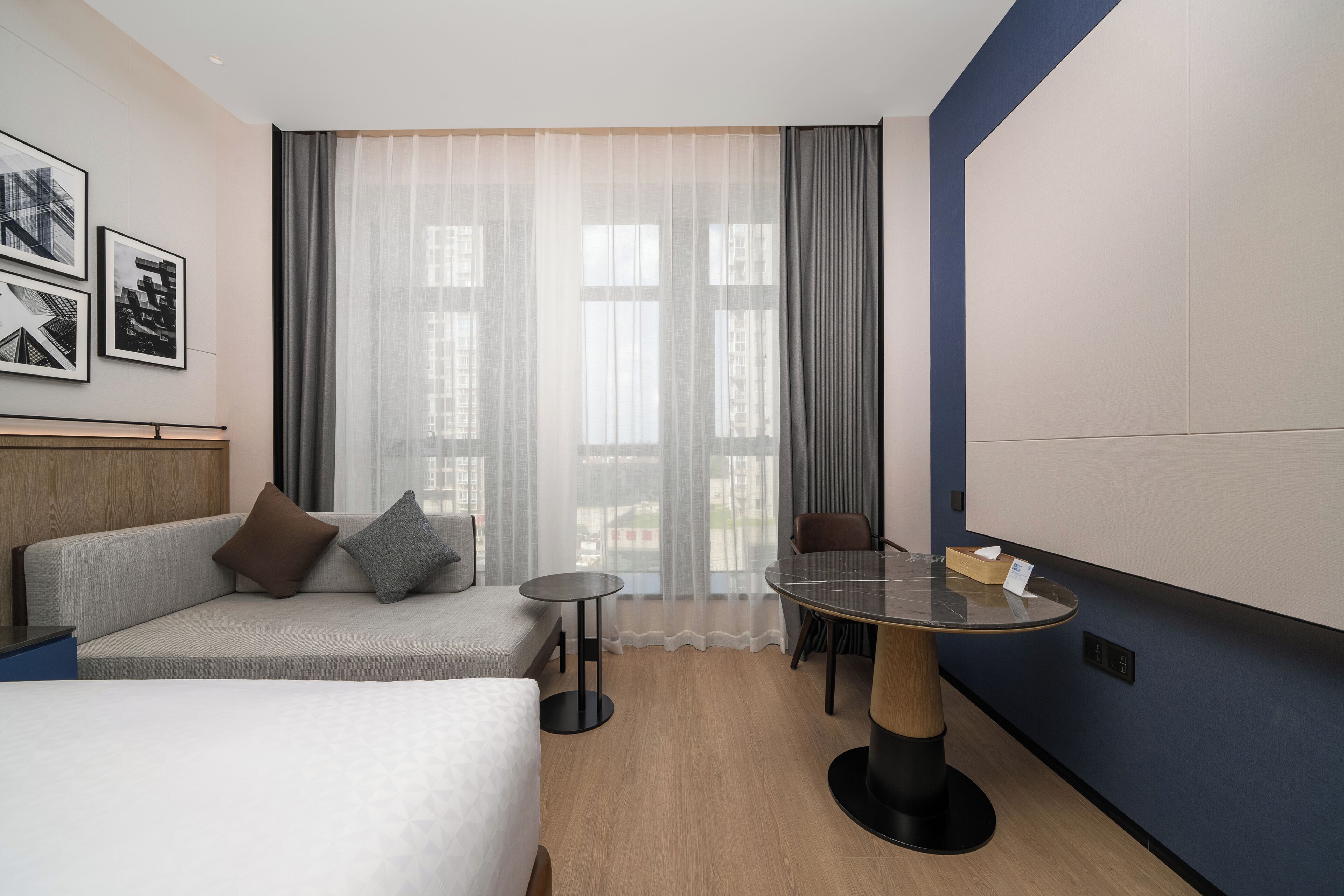 A hotel room with a bed, a sofa, a small round table, and a chair.