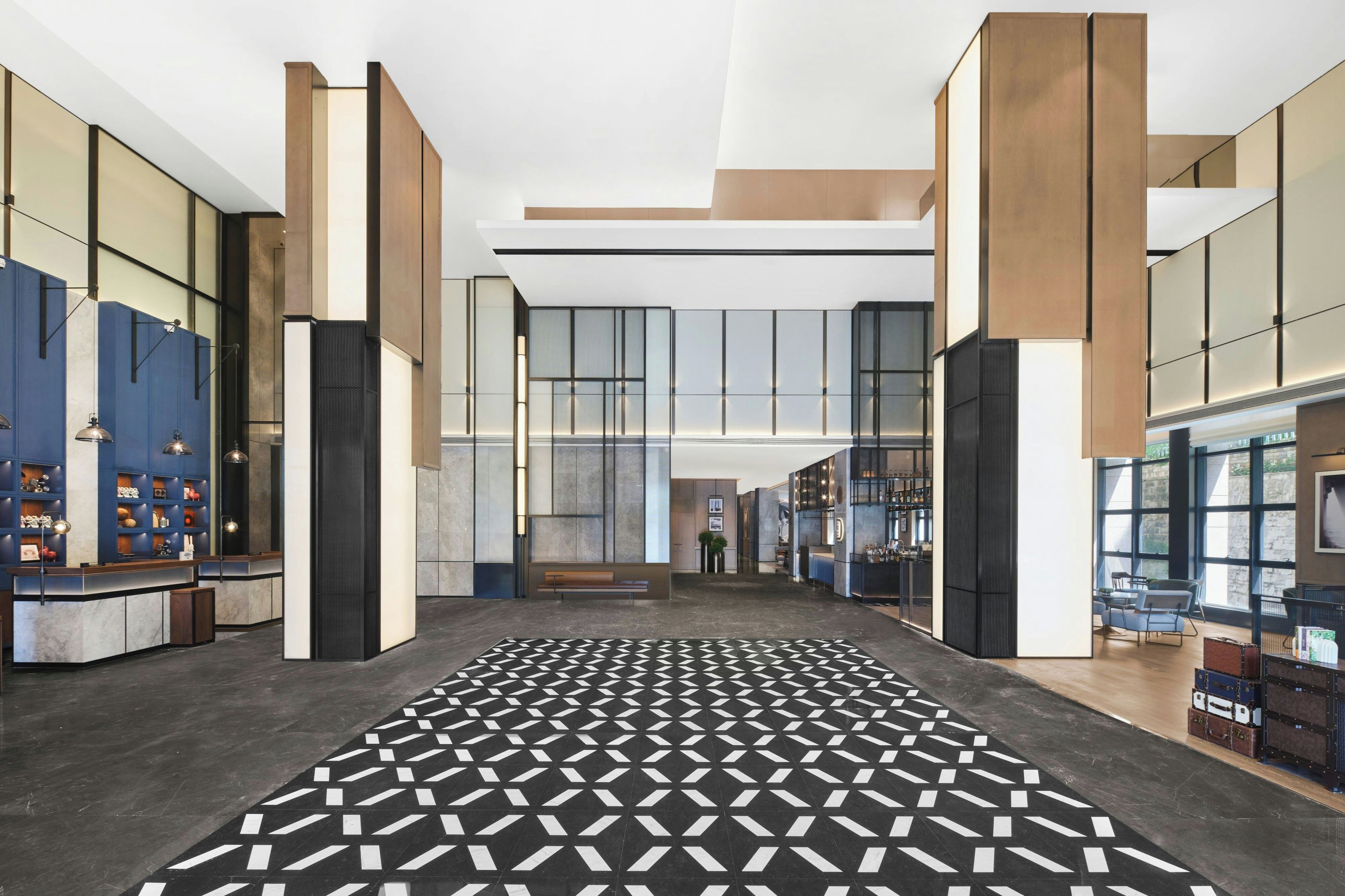 A spacious lobby with a patterned floor, a reception desk, and a seating area.
