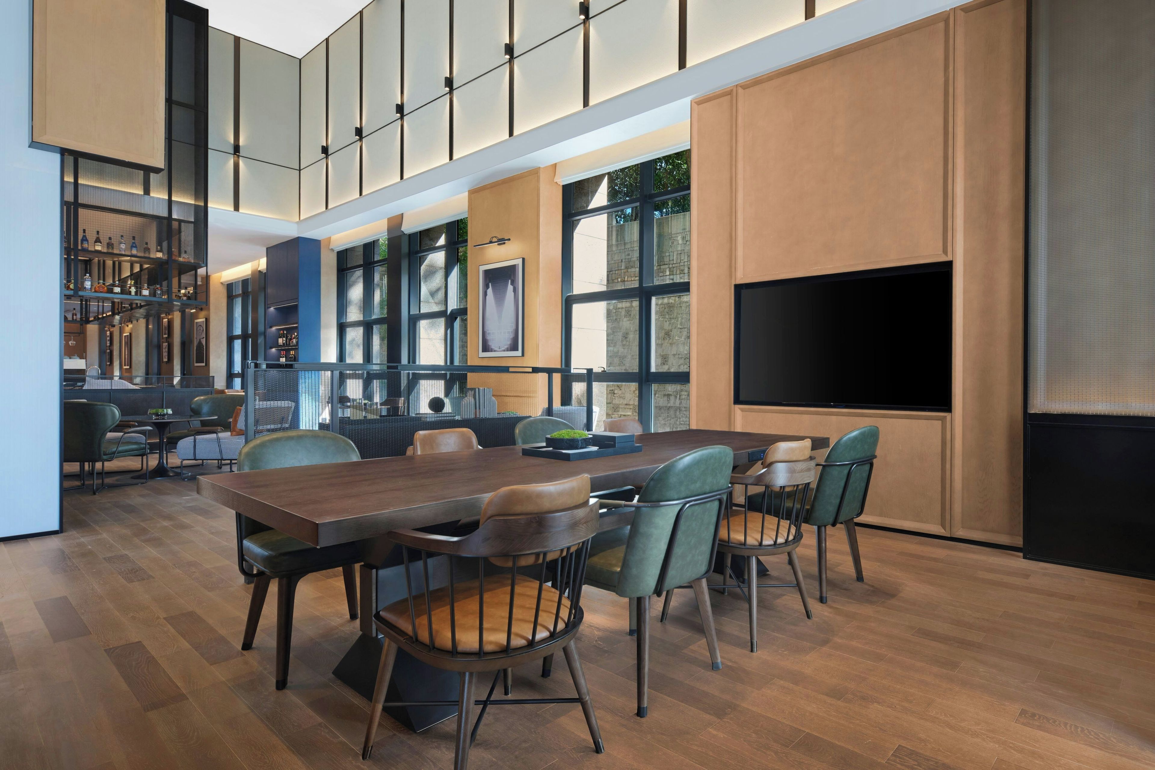 A modern dining area with a large wooden table, multiple chairs, and a television screen.