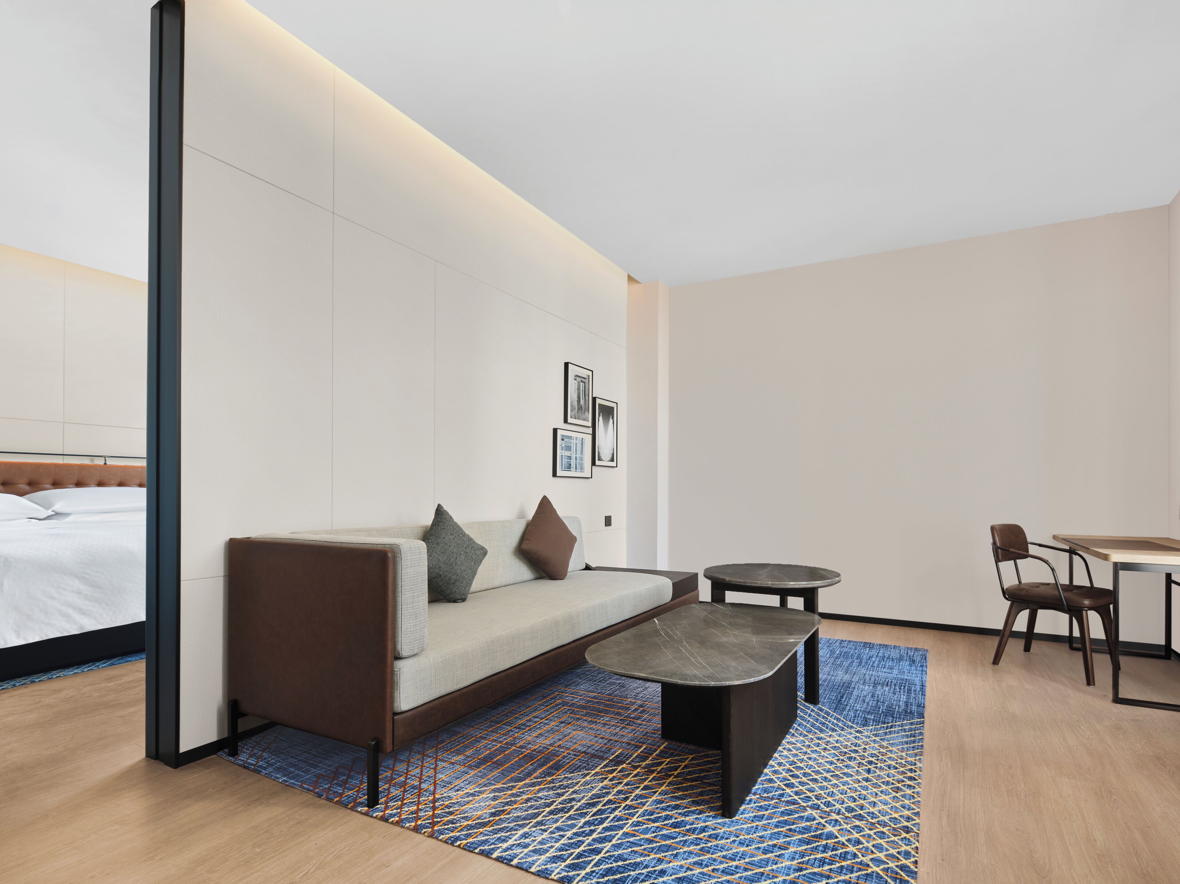 Habitación de hotel moderna con sofá, una pequeña mesa redonda, una mesita de centro y una cama con cabecera.