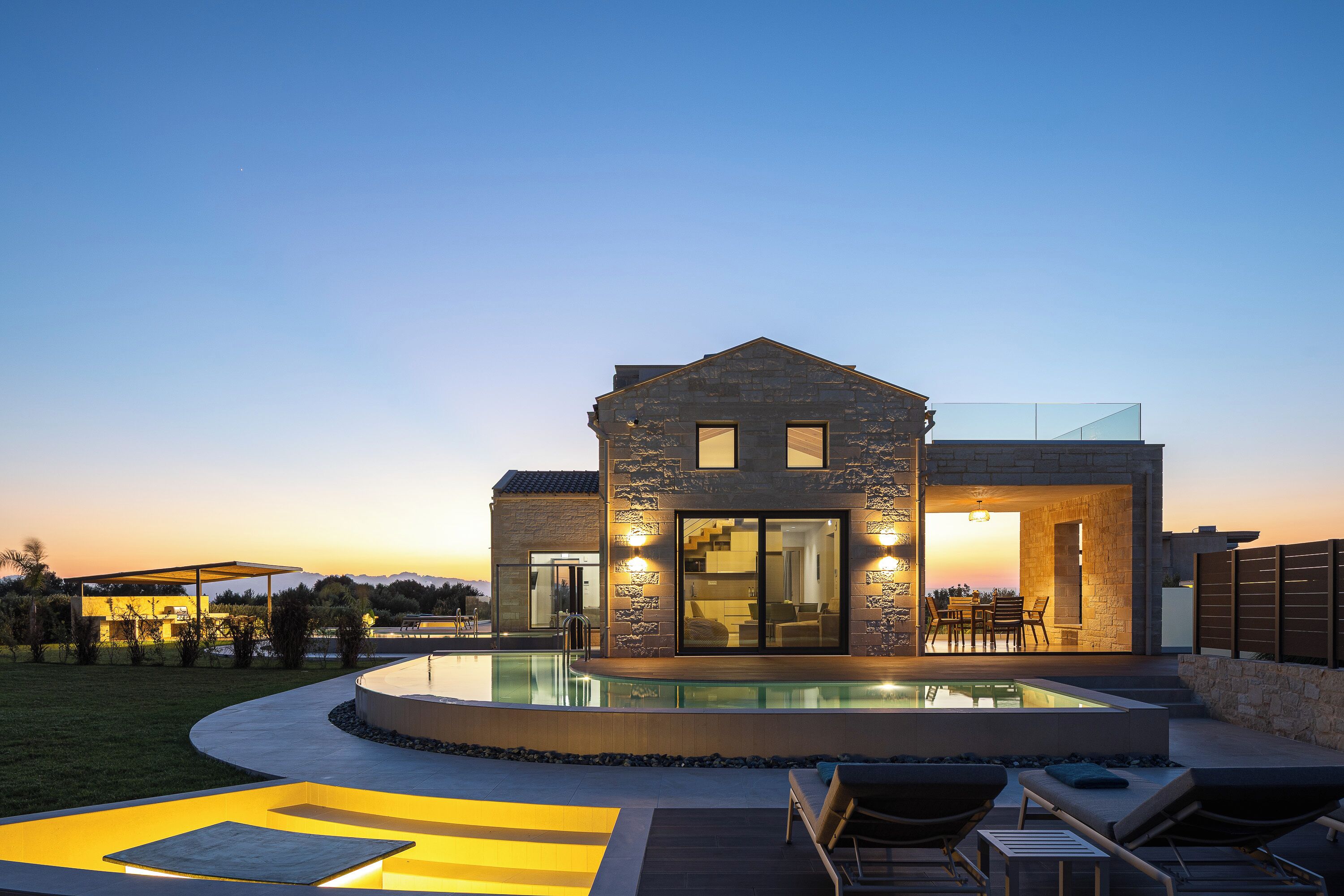 Una casa moderna con piscina, mobiliario exterior y vistas a las montañas.