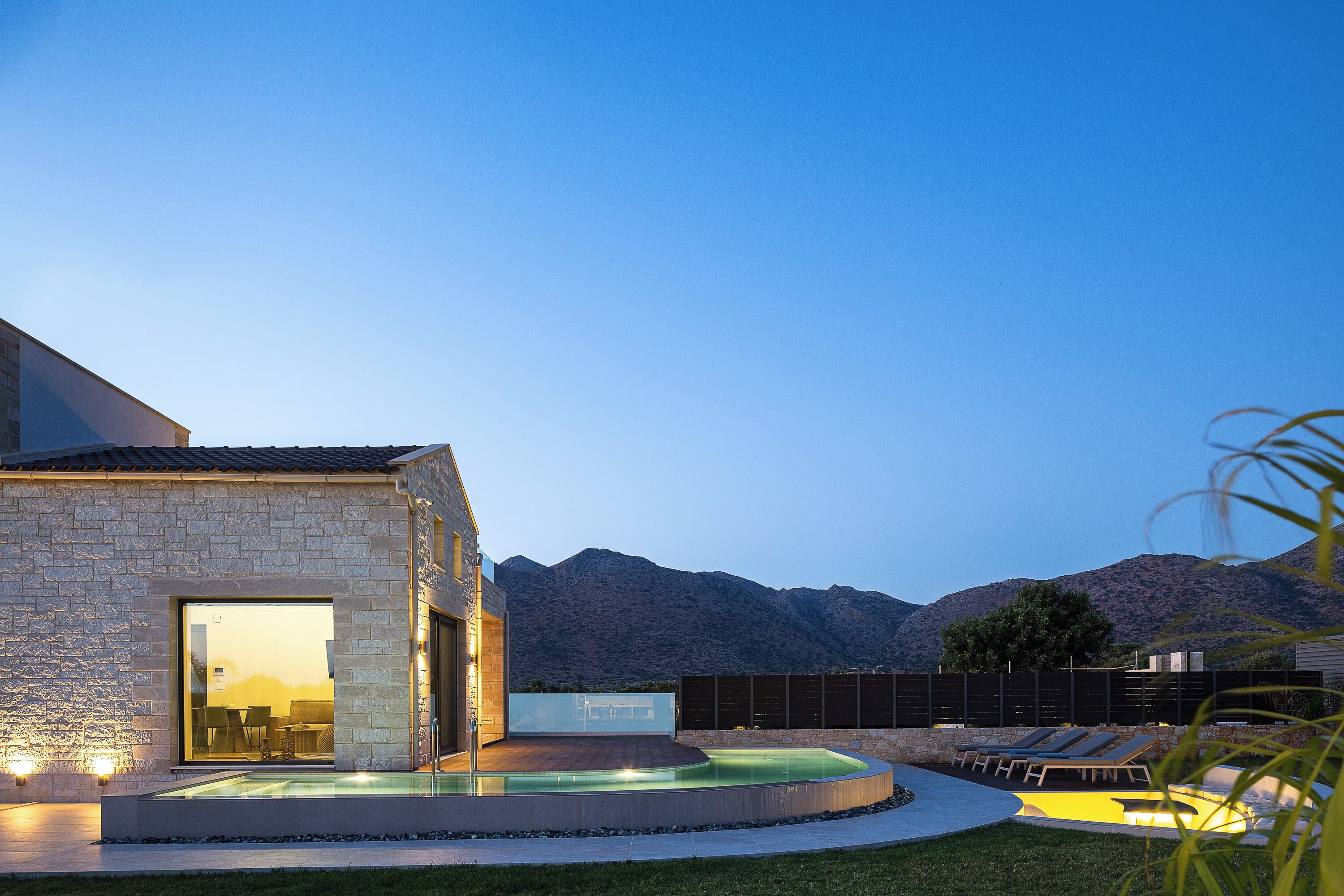 Une maison moderne dotée d’une piscine, d’un espace salon extérieur et offrant une vue sur les montagnes.
