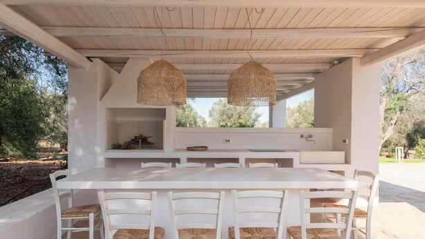 An outdoor dining area with a white table and chairs, two hanging wicker lamps, and a built-in sink. - Villa in Ostuni with 3 bedrooms sleeps 8 (Ostuni)
