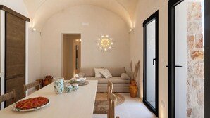 A dining area with a pizza on a plate, a table set with cups and a pitcher, and a sofa in the background. - Villa in Ostuni with 3 bedrooms sleeps 8 (Ostuni)