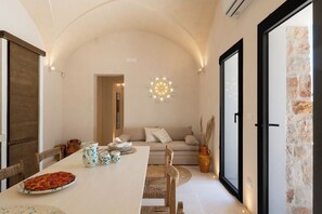A dining area with a pizza on a plate, a table set with cups and a pitcher, and a sofa in the background. - Villa in Ostuni with 3 bedrooms sleeps 8 (Ostuni)