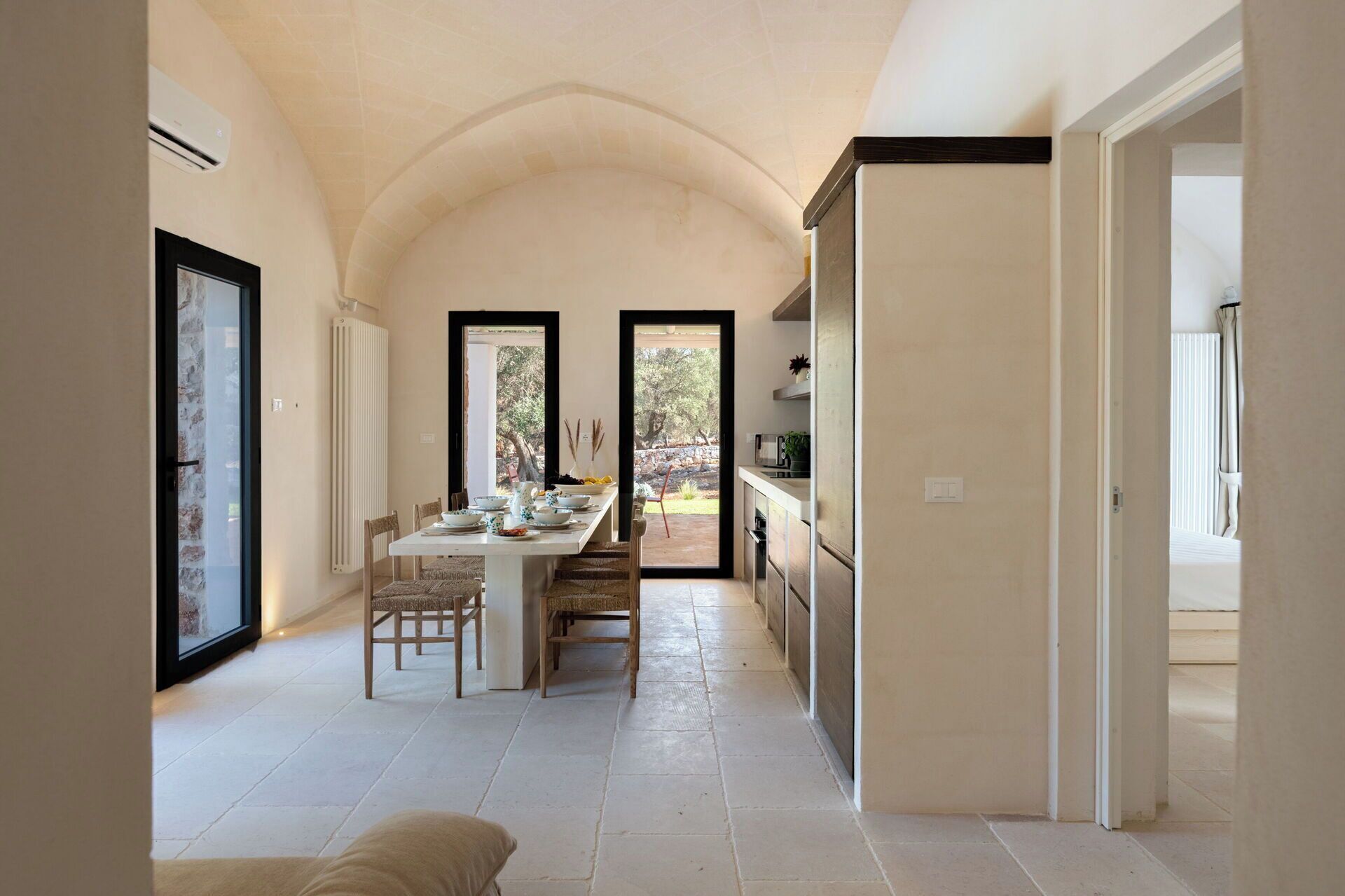 Un vaste espace à manger doté d’un haut plafond, une cuisine attenante à la salle à manger et une vue sur l’extérieur grâce à une porte vitrée.
