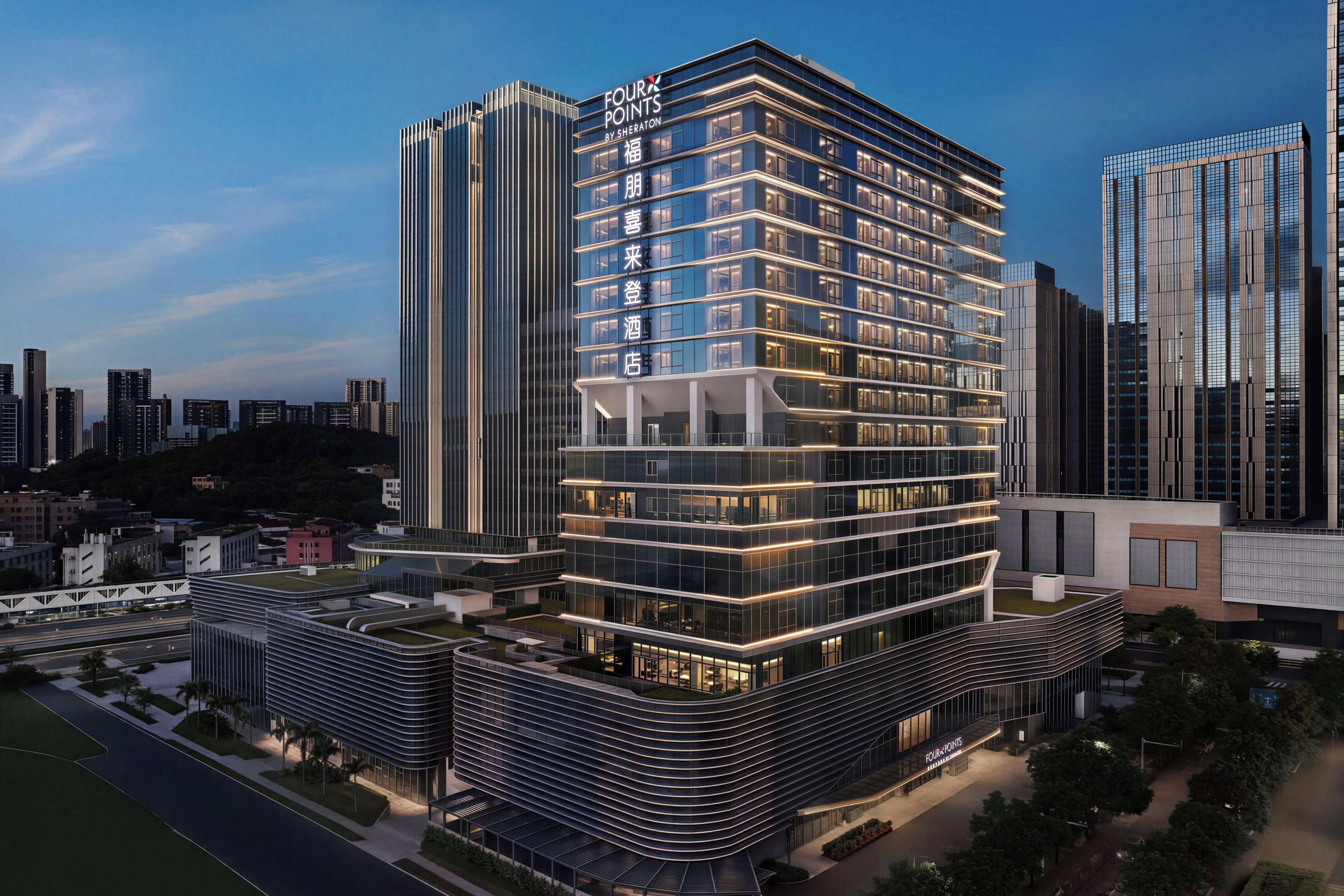 Een modern hotel met een hoekligging, met een opvallend 'Four Points by Sheraton' bord, meerdere verdiepingen en een glazen gevel.