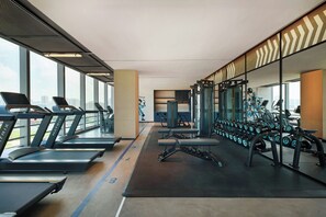 Une salle de sport équipée de tapis de course, d’appareils de musculation et d’haltères.