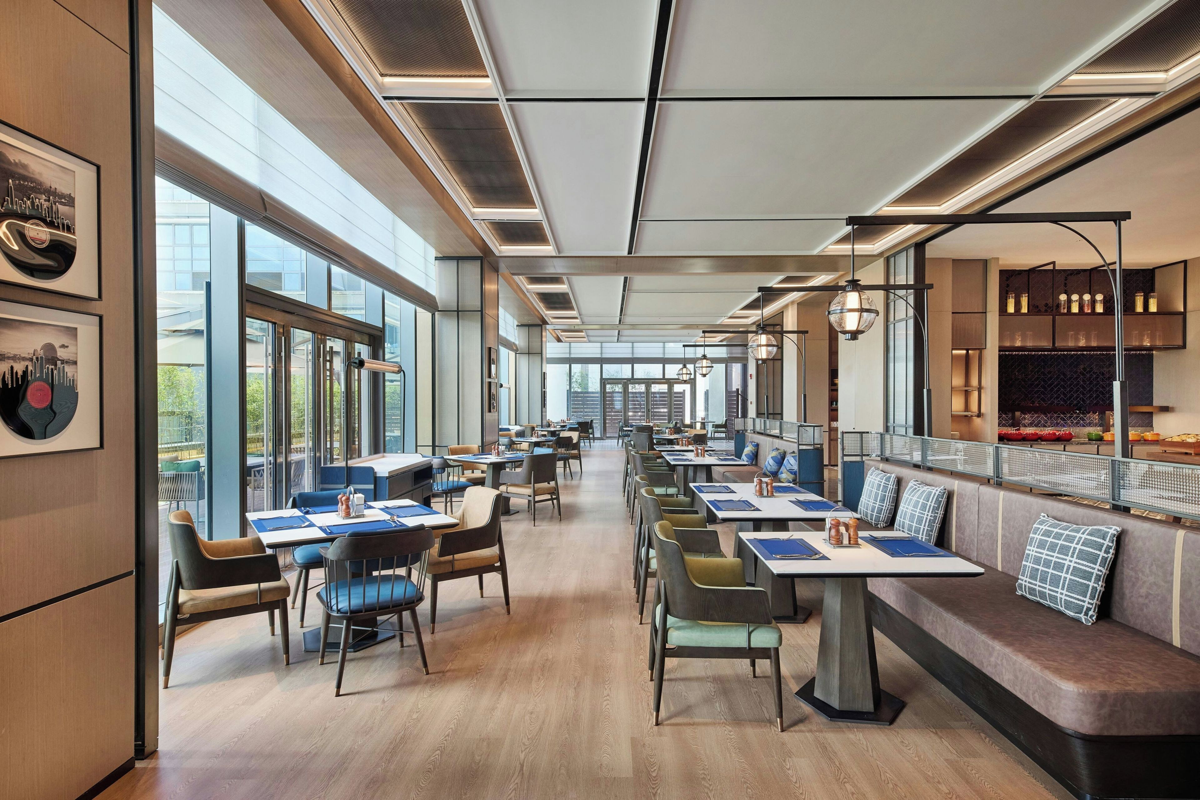 Un restaurante moderno con mesas largas, sillas y una zona de bar.