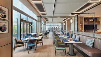 Un restaurante moderno con mesas largas, sillas y una zona de bar.